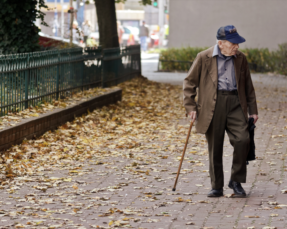 Elderly man walking down an empty sidewalk